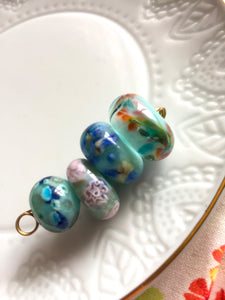 Set of 4 Handcrafted Lampwork Glass Beads in pretty light aqua blue with colorful spots, swirls, and floral embellishments.